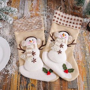 Plaid snowman Christmas stockings with hanging loop on vintage wood and pine backdrop