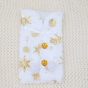 Close-up of white plush Christmas wine bottle cover with gold snowflakes and bow