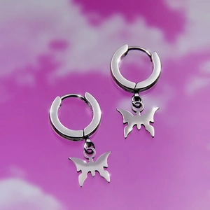 Detail of silver stainless steel hoop earring with a butterfly pendant on cloud background