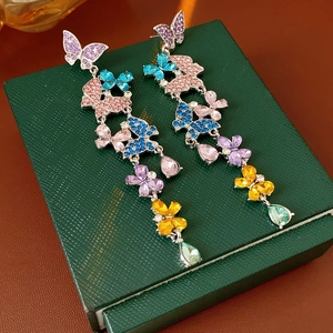 Detail of colorful butterfly drop earrings with rhinestones on a green jewelry box