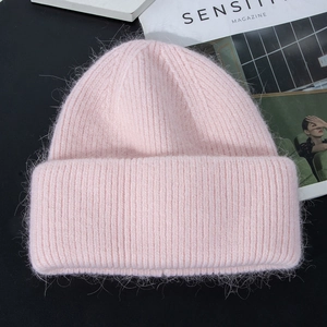 Close-up of the plush rabbit fur texture on a light pink knitted winter beanie hat