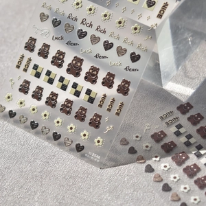 Macro view of 5D embossed nail stickers with cute bear, heart, and checkerboard patterns