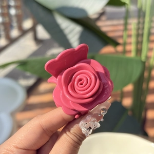 Close-up of pink rose hair claw clip made of glossy resin in an outdoor setting