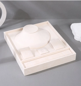 Detailed top view of a beige velvet jewelry tray with necklace stand and ring slots