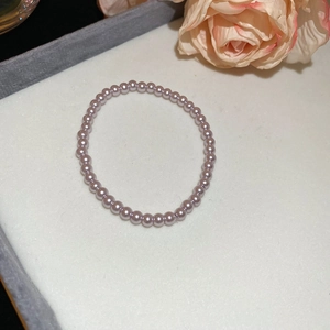 Close-up of lavender pearl necklace on white velvet display with pink rose accents