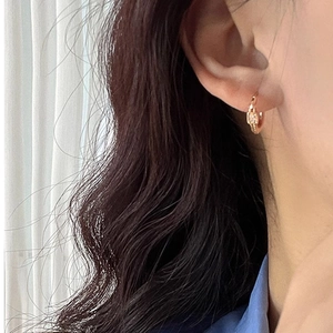 Macro detail of a gold geometric square hoop earring with micro-inlaid stones on an ear