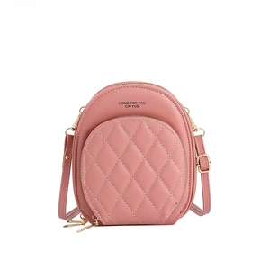 Detailed view of pink crossbody bag with quilted diamond pattern and golden zippers