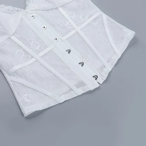 Close-up of white lace corset top featuring intricate embroidery and metal hook-and-eye closure
