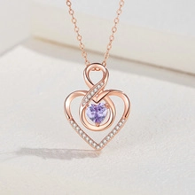 Macro shot of rose gold heart and infinity pendant with heart-shaped purple gem