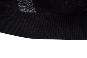 Gros plan sur le pull en maille noire montrant l'ourlet côtelé et les détails du tissage