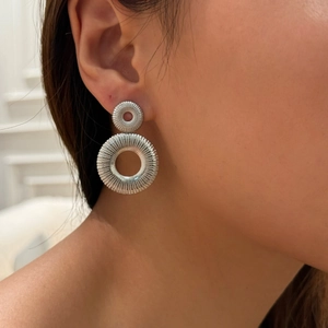 Silver textured double hoop earrings in pleated style worn by a model in profile view