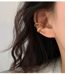 Detailed view of layered gold ear cuffs featuring white pearls and zircon on model's ear