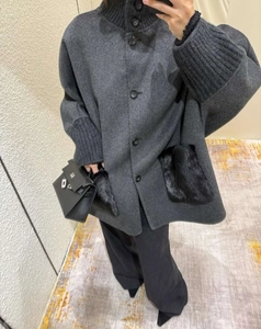 Detail of dark gray wool coat with knit high collar and black faux fur pockets