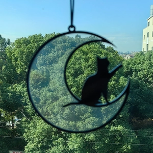 Detail of hanging black moon and cat silhouette suncatcher with rainbow prism effects