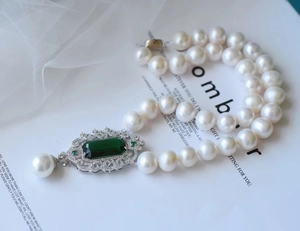 Macro shot of emerald-cut green gemstone on a vintage pearl necklace with micro-pave setting