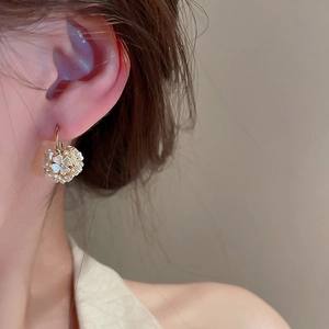 Gros plan de boucles d'oreilles boules de fleurs dorées avec cristaux sur un mannequin