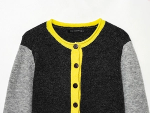 Detailed view of color-block knit cardigan with yellow ribbing and gray patchwork texture