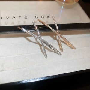 Macro shot of silver and rose gold X-shaped hair clips with sparkling pavé rhinestones