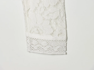 Close-up detail of white lace fabric featuring intricate floral crochet and hollow weaving
