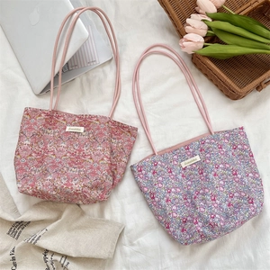 Vue à plat de sacs fourre-tout en toile florale avec anses en corde et ordinateur