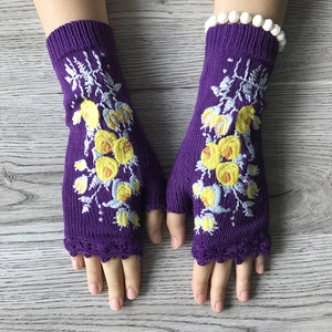 Winter purple knitted fingerless gloves with yellow flower embroidery on wooden background