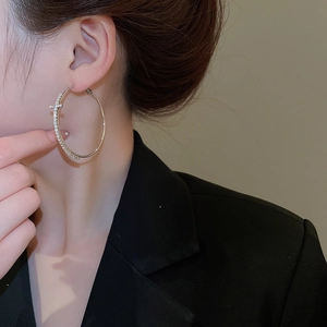 Gros plan d'une créole en argent avec pendentif croix serti de diamants sur mannequin