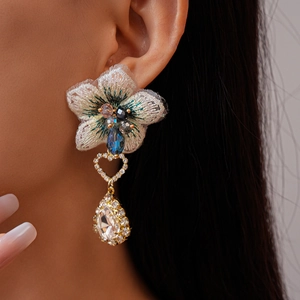 Détail de boucles d'oreilles fleur brodée avec zircon goutte et strass sur modèle