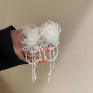 Detail of white camellia earrings with mesh petals and hanging beaded tassels