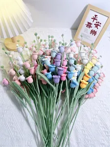 Macro shot of colorful handmade crochet lily of the valley flowers on a white fabric background