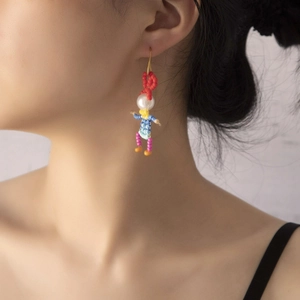 Close-up of colorful handmade beaded doll earrings with pearl head on female model