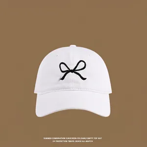 Close-up of white canvas sun hat with minimalist black butterfly embroidery detail