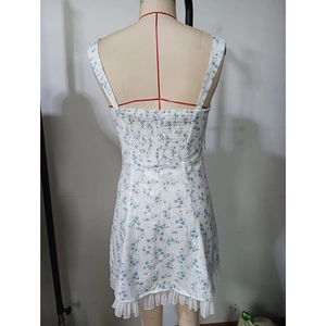 Detail of white floral summer dress featuring elasticated ruched back and ruffle hem