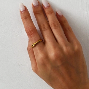 Minimalist 14K gold wave ring with irregular liquid design worn on hand against white wall