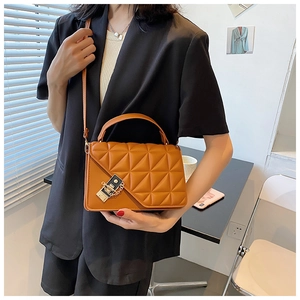 Détail d'un sac bandoulière orange matelassé avec chaîne dorée sur mannequin
