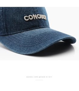 Macro shot of 3D CONQUER embroidery on premium blue denim fabric baseball cap