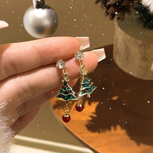 Close-up of gold Christmas tree earrings with green enamel and sparkling rhinestones
