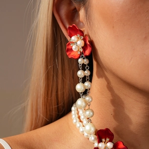 Close-up of red floral earrings and pearl necklace with sparkling rhinestone details