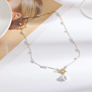 Close-up of golden necklace featuring purple beads, toggle clasp and baroque pearl pendant