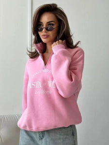 Detail eines rosa Sweatshirts mit halbem Reißverschluss, weißem Text und trendigem Kragen