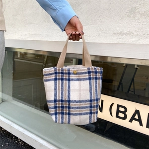 Detail view of mini plaid woolen handbag with bronze snap button and woven handle