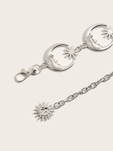 Détail d'une chaîne de taille en métal argenté avec pendentifs soleil et lune gaufrés