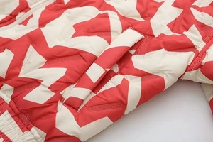 Détail d'une doudoune à imprimé géométrique rouge et blanc avec poche latérale et matelassage