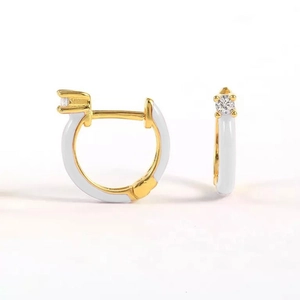 Detail of gold hoop earrings with white enamel coating and a single round zircon stone