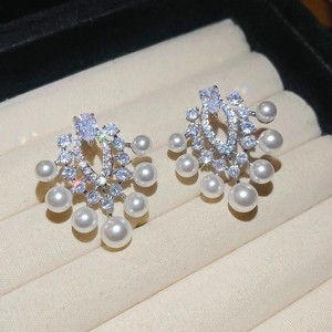 Makroaufnahme von Vintage-Perlenohrringen mit Zirkonsteinen auf einer beigen Box