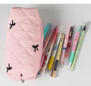 Close-up of pink quilted pencil case with bow embroidery and large zipper opening