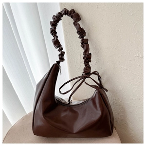 Detail der dunkelbraunen Hobo-Tasche mit geriffeltem Griff und seitlichen Knotenschleifen