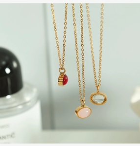 Macro view of three minimalist gold necklaces with red, pink, and clear round gemstones