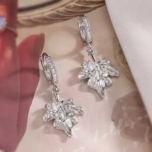 Silver maple leaf drop earrings with sparkling cubic zirconia on stylish fabric background