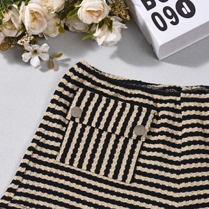 Detail van taillezak op gestreepte gebreide shorts met metalen knoop en textuur