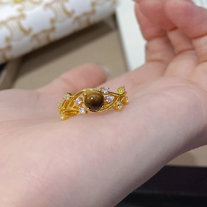 Close-up of a gold-plated vine ring featuring a brown tiger eye stone and white zircons